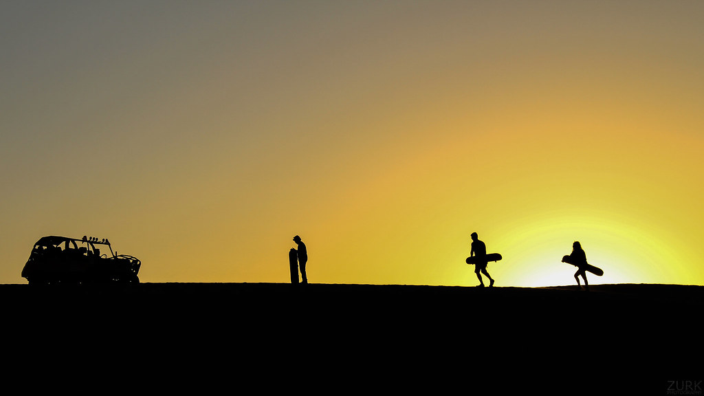 People silhouetted on a dune ridge at sunset