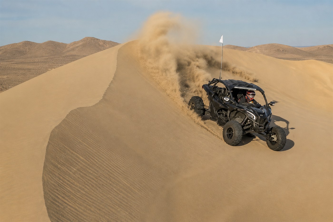 Can-Am vehicle driving through desert dunes