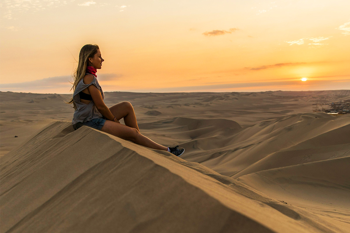 Traveler looking across the dunes near Huacachina at sunset